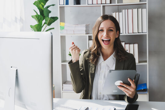 Overjoyed young businesswoman with digital tablet expressing excitement rejoicing in home office, Excited business woman feel euphoric reading good news online.