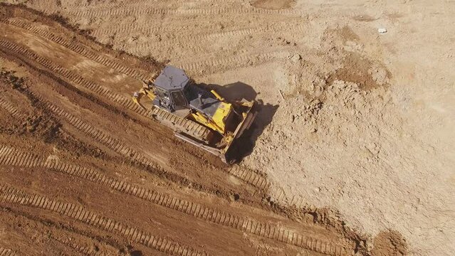 Aerial view of earthmoving bulldozer.
Crawler bulldozer working in sand quarry. Top view of bulldozer mining sand at industrial area. Mining machinery in sand mine. Sand mining industry. Earth mover w