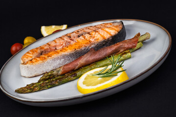 Fresh cooked delicious salmon steak with asparagus, spices and herbs baked on a grill. Healthy seafood food.