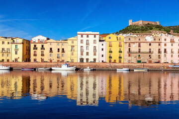 Obraz premium River with Homes and Apartments in Touristic Town. Bosa, Sardinia, Italy. Sunny Fall Season Day. Panorama