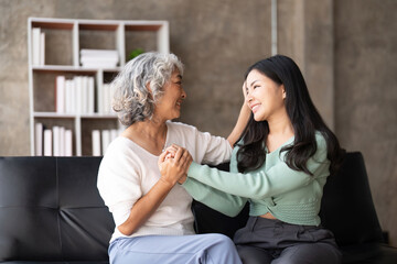 Happy daughter and mother having fun in living room, smiling mother hugging young grown daughter bonding chatting relaxing encourage each other at home together
