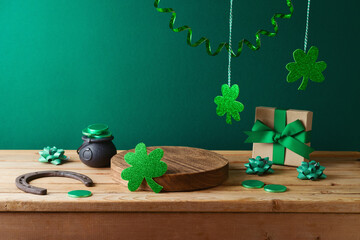 St Patrick's day concept with wooden log, shamrock and gift box on wooden table over green background. Holiday mock up for design and product display