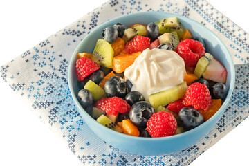In a blue bowl, a freshly prepared fruit sliced ​​salad of kiwi, apples, tangerines, raspberries and blueberries with yogurt.