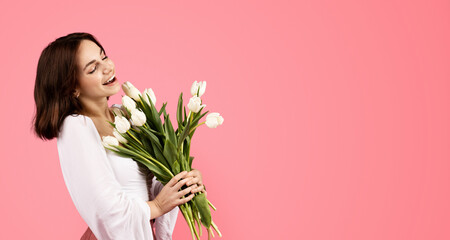 Glad young european woman smelling bouquet of flowers, enjoy lifestyle and aroma of white tulips