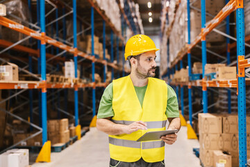 A warehouseman is tracking orders online on tablet.