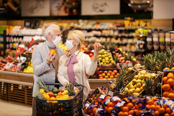 A senior couple during pandemic purchasing fruits at the supermarket.