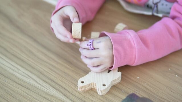 A girl makes a toy out of wood at a master class in kindergarten