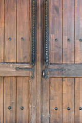 Fototapeta na wymiar Old, faded classical, brown, wooden door with iron door handle. Door textures and background.