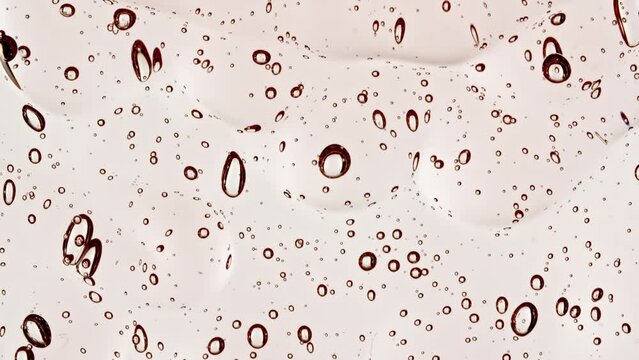 Pink Transparent Cosmetic Gel Fluid With Molecule Bubbles Flowing On The Plain White Surface. Macro Shot. High quality 4k footage