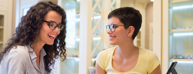 	
Young beautiful woman choosing eyeglasses in the optical shop