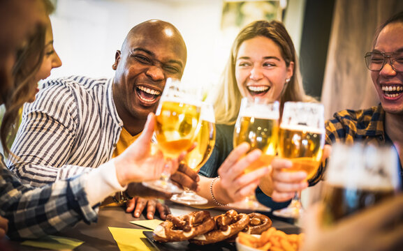 People group drinking beer at brewery bar restaurant - Beverage concept with happy friends enjoying time together and having genuine fun at cool pub venue - Warm sunshine filter with focus on left guy