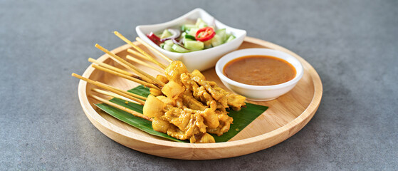 thai satay skewers with grilled pork and dipping sauces served on banana leaf plate