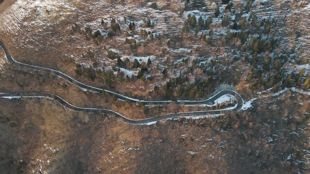Aerial view of a scenic forest road on mountainside in wintertime at sunset with snow on Mount Terminio, Serino, Avellino, Irpinia, Campania, Italy.