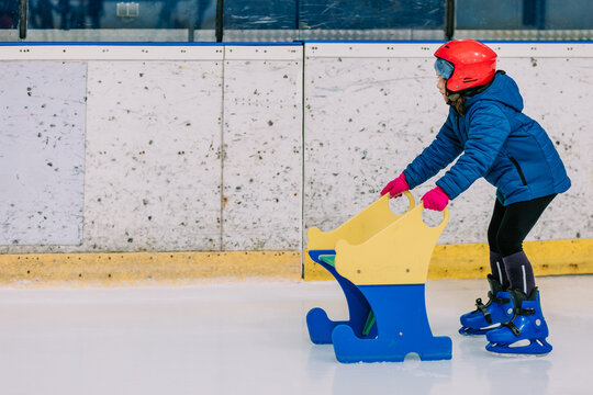 Girl skating with special stand on ice rink