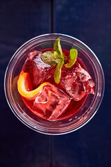 red summer cocktail with lemon and mint top view on blue brane stand, measuring cup, strainer, jiger