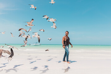 Man practicing yoga on the beach surrounded by seagulls