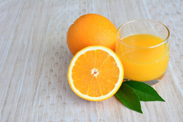 homemade orange juice in drinking glass with oranges and green leaf on pastel background