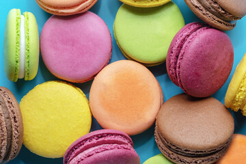 multicolored macaroons lying on colored background, French biscuit dessert made of almonds, close-up, top view, flat lay