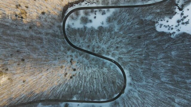 Aerial view of a serpentine road crossing a forest in wintertime with snow on Mount Terminio, Serino, Avellino, Irpinia, Campania, Italy.