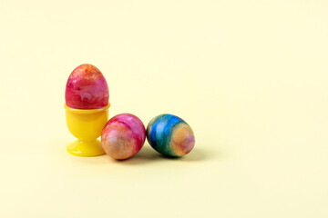 Three Easter multicolored eggs on a yellow background. Happy Easter concept. Greeting card.