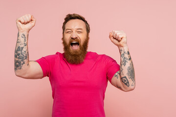 joyful bearded man with closed eyes showing triumph gesture and screaming isolated on pink.