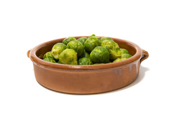 A pile of boiled brussels sprouts, served in a clay bowl. Isolated on a white background. Healthy food concept.