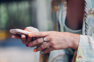 Fashionable woman with colorful nail polish checks social networks on phone.