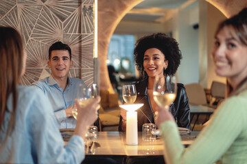 Friends Enjoying Dinner and white wine at a Restaurant