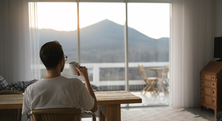 a man is resting in a country house in the mountains and drinking tea sitting on an armchair