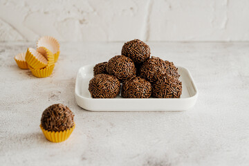 Brigadeiro de chocolate empilhados do prato de porcelana em fundo branco 