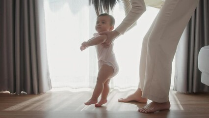 A baby girl learning first steps walk with mother, family, child, childhood and parenthood concept