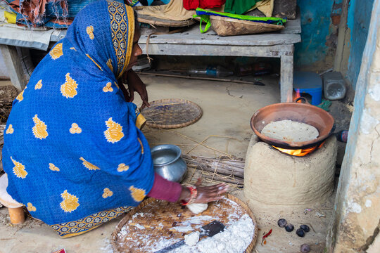 women making rice bread in traditional soil vessels at wood fire from different angle at village