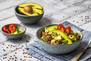 Lentil salad with avocado and red pepper on gray tiles background.  Vegetarian and vegan food.
