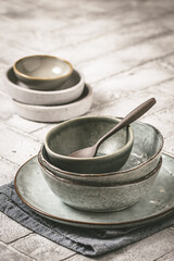 Gray stoneware plates and bowls on a rustic table, vertical with copy space