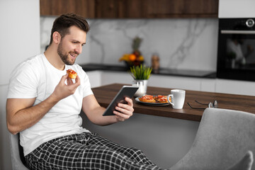 Man using tablet while having breakfast at home kitchen