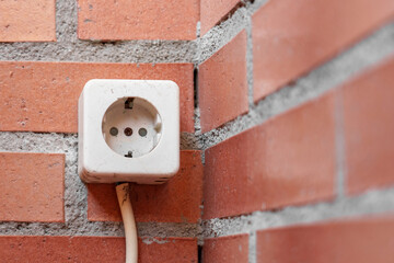 Electric socket outside the garden building on a brick wall