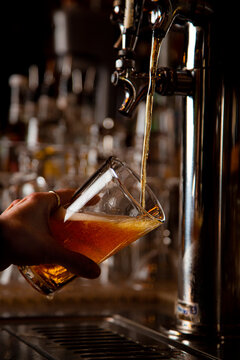 Beer pouring into tilted pint glass at brewery bar