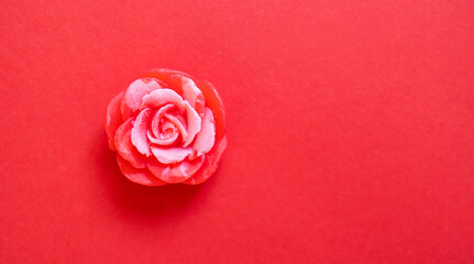 Handmade soap. Solid soap in the shape of a red rose flower. Red background.