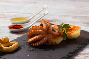 Close-up of Galician style octopus on a black slate plate. Typical Spanish food.