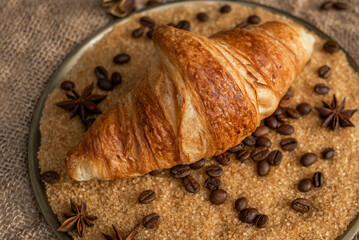 Freshly baked French croissant on a copper platter. Croissant in cane sugar with coffee beans