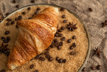 Freshly baked French croissant on a copper platter. Croissant in cane sugar with coffee beans