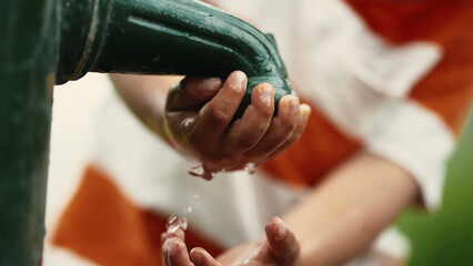 Child washing hand at public water faucet at park. kid closeup hands pouring water