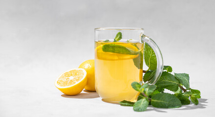 Aroma a glass of lemon tea with mint on a light background. The concept of a healthy breakfast drink for immunity and vigor.