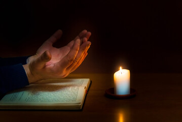 Religious concepts.The young payer prayed on the Bible in the room and lit the old candle to...