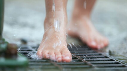 Barefoot Child feet standing by public water faucet pouring liquid in slow motion