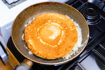 American Pancake burn on the pan,homemade pancake fried in a pan in the kitchen.Delicious thin pancake in frying pan on gas stove.Closeup.