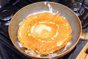American Pancake burn on the pan,homemade pancake fried in a pan in the kitchen.Delicious thin pancake in frying pan on gas stove.Closeup.