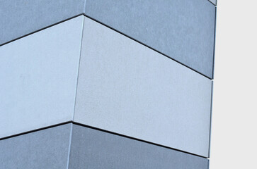 plasterboard cladding of a building with a expanded metal lattice structure. galvanized gray nets protect the industrial building. Blue sky in contrast to a silver background, wall, corner, slanted