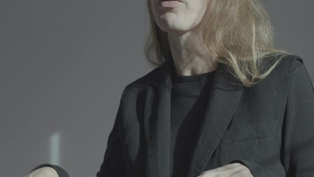 A woman in a business suit speaks and gesticulates actively. The transition from the hands at the level of the abdomen to the face. Emotional self-expression.