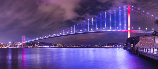 Panoramic long exposure of 15 July Martyrs Bridge (Turkish: 15 Temmuz Sehitler Koprusu) on parliament night blue hour cloudy sky in Istanbul, Turkey. Istanbul Bosphorus Bridge. 